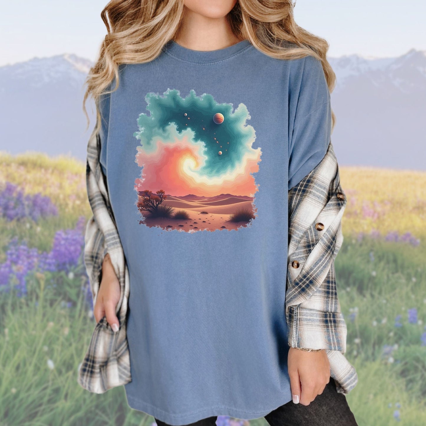 A woman wearing a vintage-style blue tee with a cosmic swirl pattern, paired with a plaid shirt.