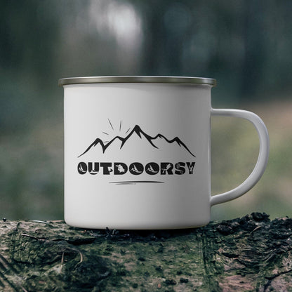 White mug with 'Outdoorsy' design on a log in a forest setting