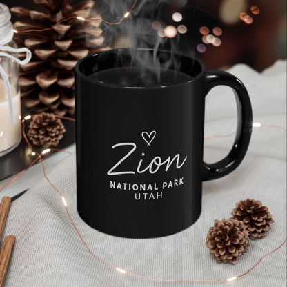 Black mug with 'Zion National Park Utah' text on a table with decorative items.