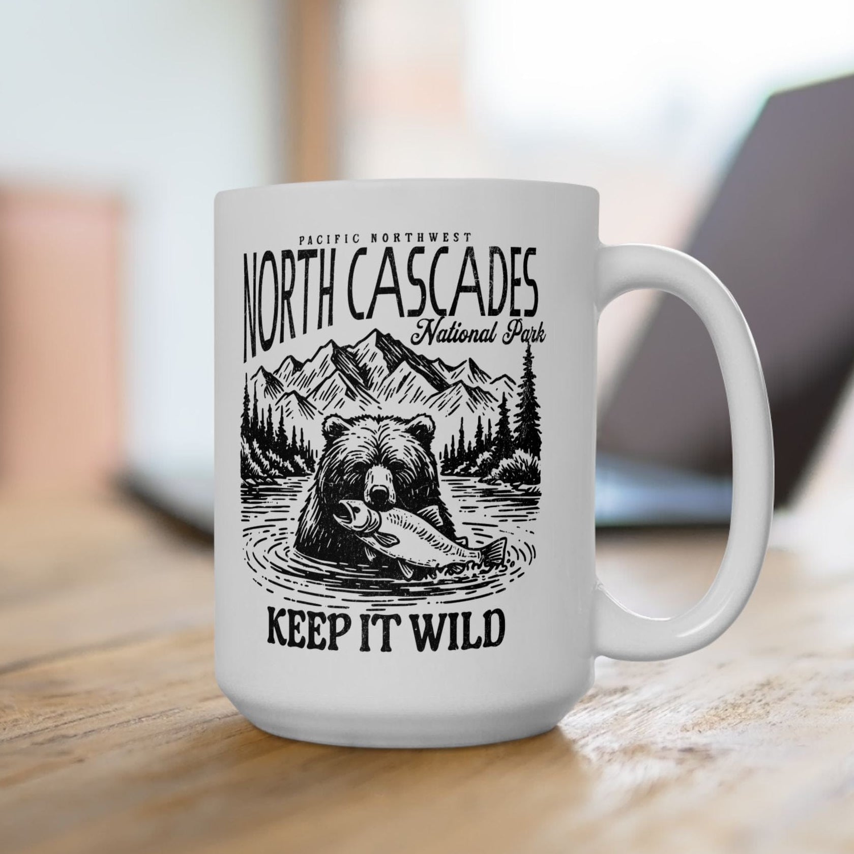 White mug with bear and mountain design and text on a wooden surface