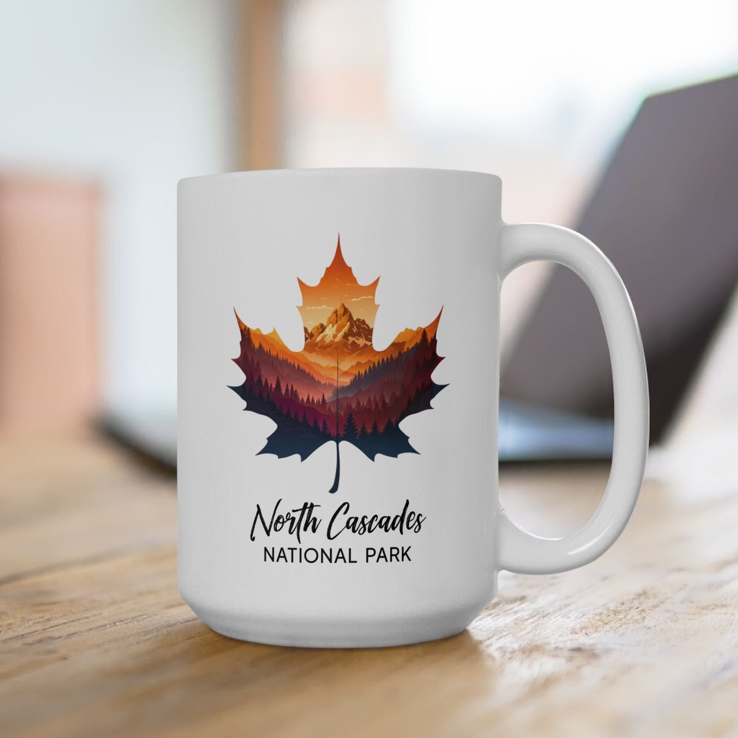 White mug with a colorful leaf design and 'North Cascades National Park' text on a wooden surface.