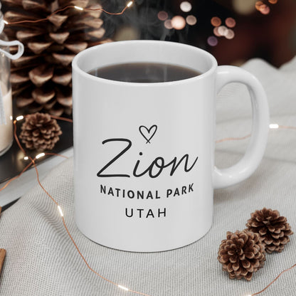 White mug with 'Zion National Park Utah' text on a table with decorative items.