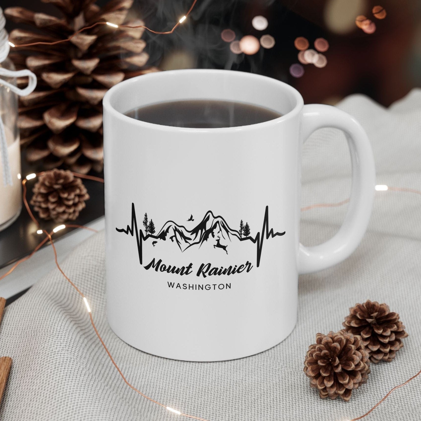 White mug with 'Mount Rainier Washington' design on a table with decorative items