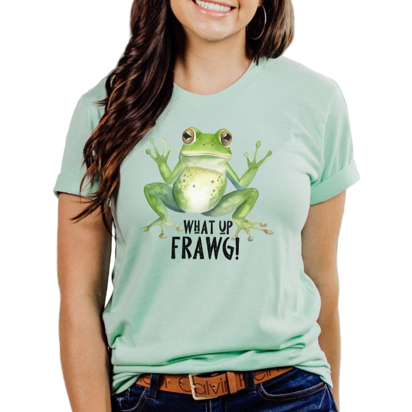 A person wearing a light green t-shirt with a large green frog graphic and the text 'What Up Frawg!' on it.