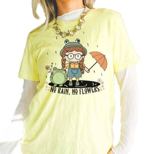 A woman wearing a yellow t-shirt with a cartoon character and the text 'No Rain, No Flowers' printed on it.