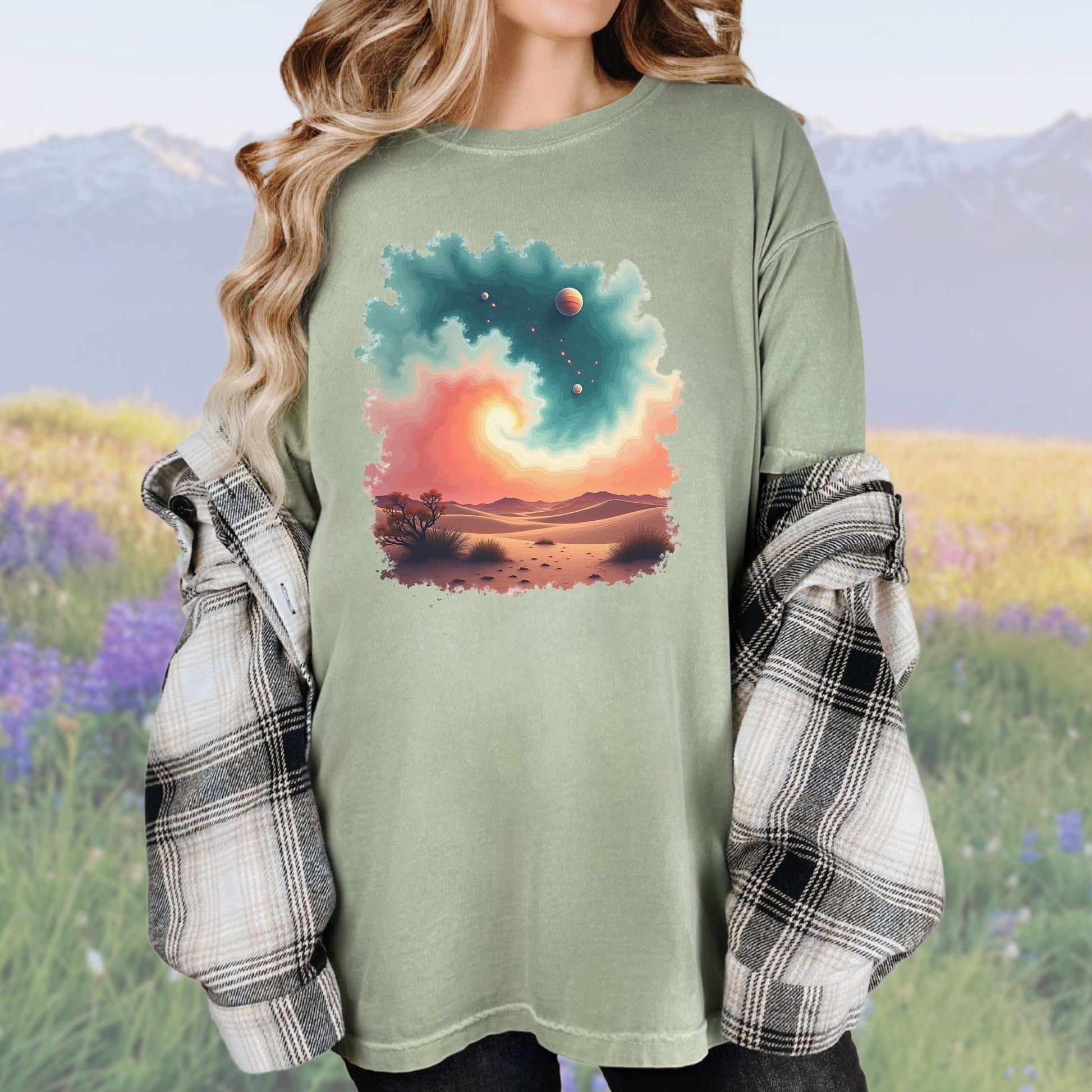 A woman wearing a vintage-style light green tee with a desert swirl pattern, paired with a plaid shirt.