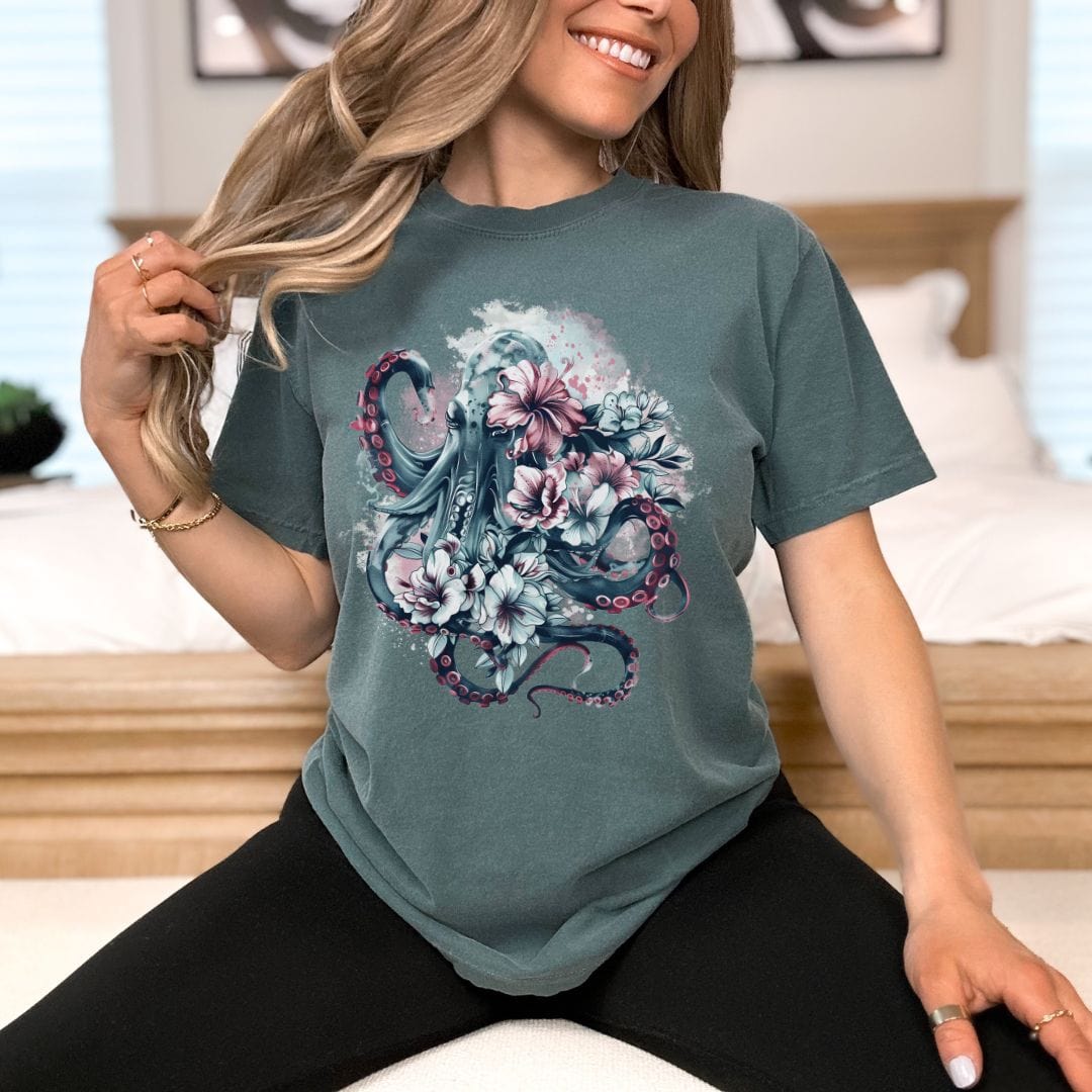 A person wearing a light blue green t-shirt with a vintage floral Kraken design.