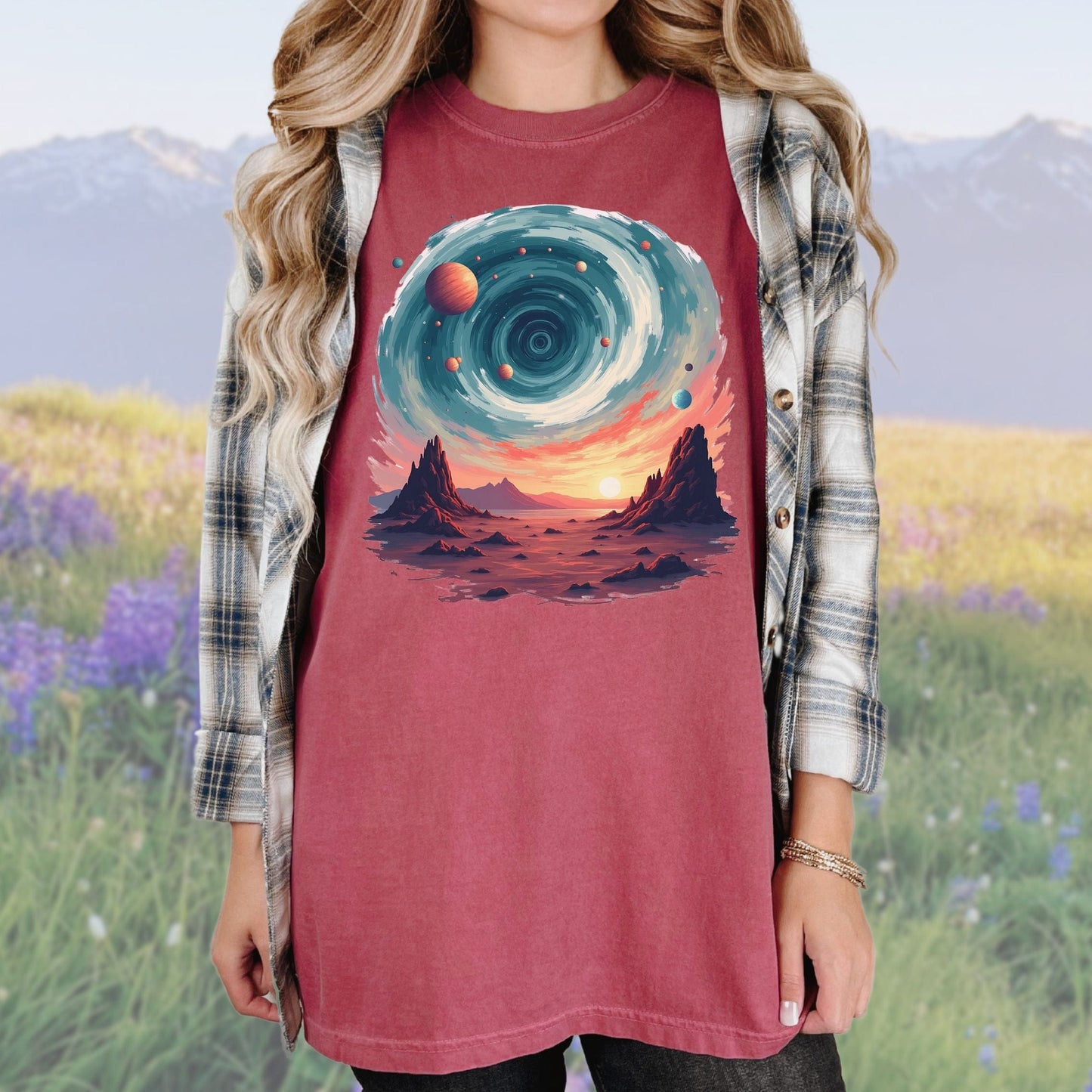 A person wearing an brick colored t-shirt with a vintage cosmic swirls graphic, paired with a plaid shirt.