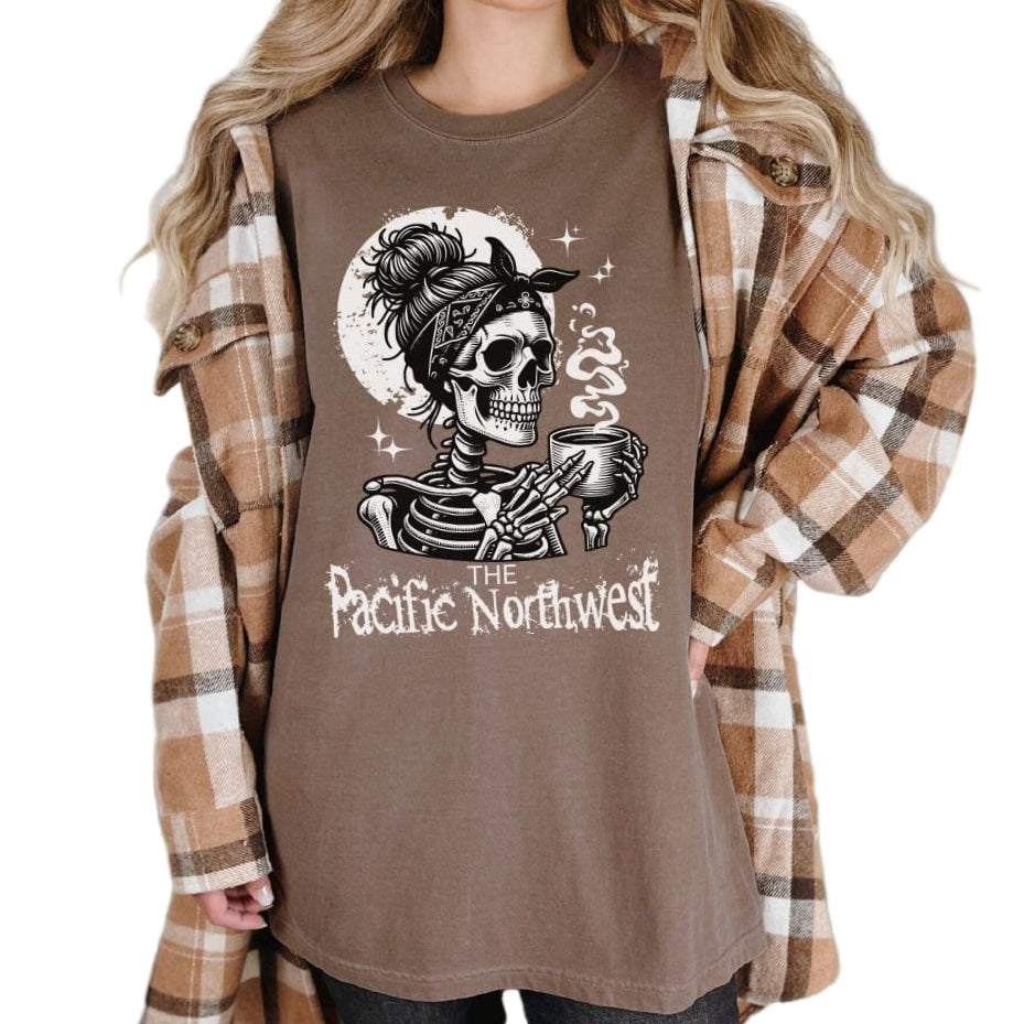 A person wearing a blue vintage-style tee with a graphic of a skull holding a mug and the text 'PACIFIC NORTHWEST'.