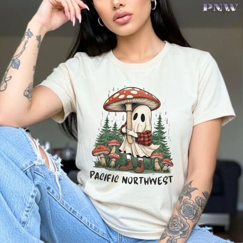 Person wearing an ivory t-shirt with a ghost and mushroom graphic and 'Pacific Northwest' text.