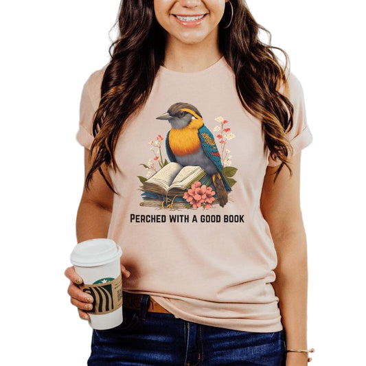 A woman wearing a peach colored  tee with a printed bird and book design.