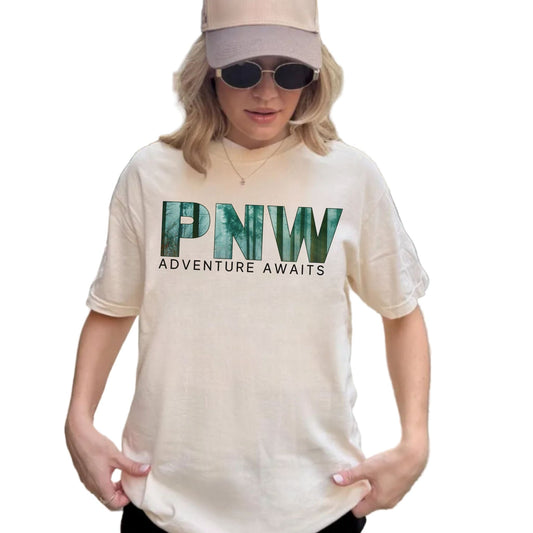 Person wearing a white t-shirt with 'PNW Adventure Awaits' text on the front.