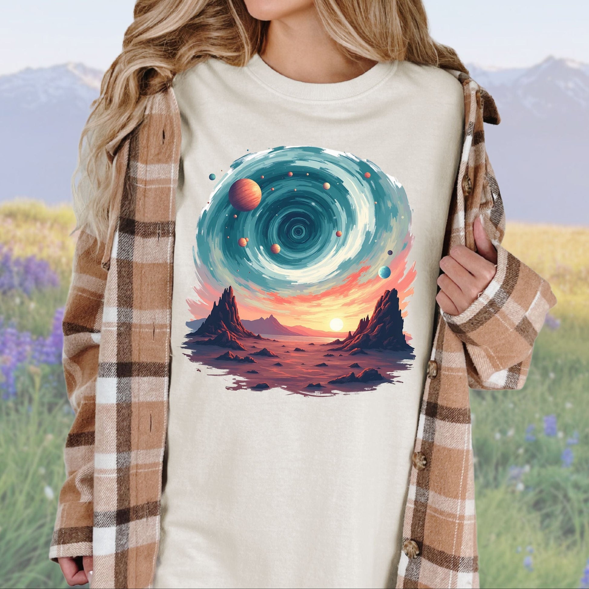 A person wearing a ivory t-shirt with a vintage cosmic swirls graphic, paired with a plaid shirt.