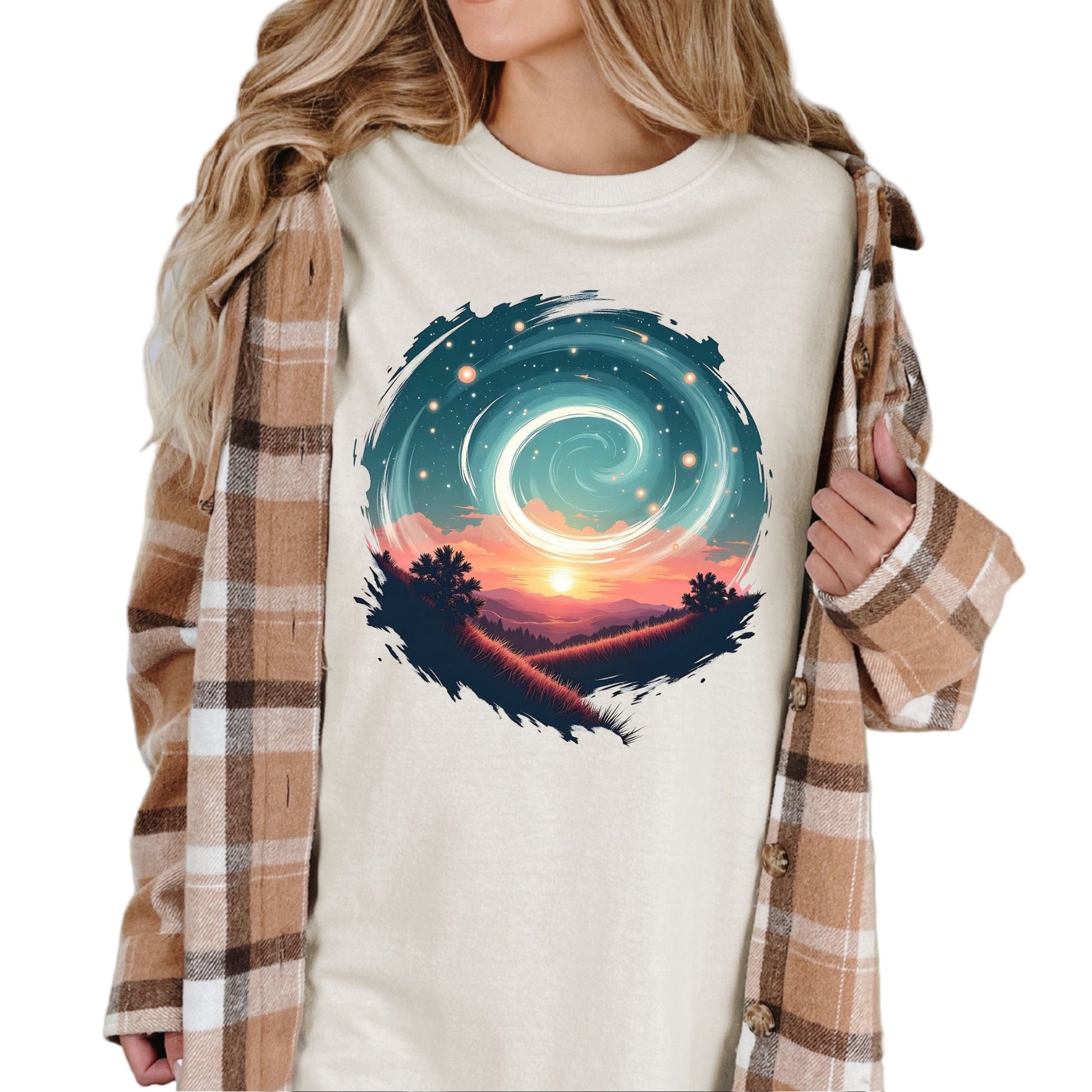 A person wearing a vintage-style graphic tee in an ivory color with a swirl pattern in the design, standing in a field with mountains in the background.