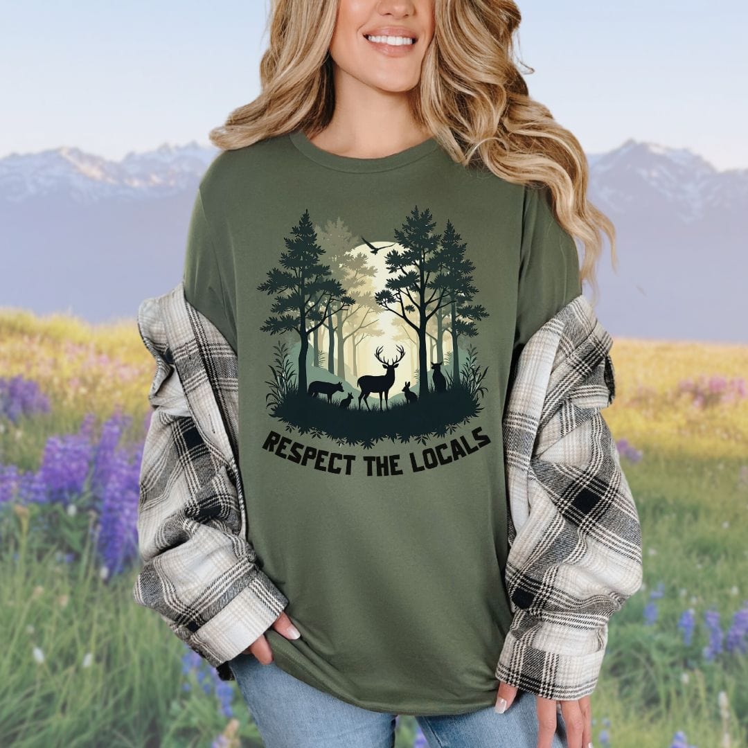 A person wearing a green t-shirt with a graphic of a forest and deer and the text 'RESPECT THE LOCALS'.