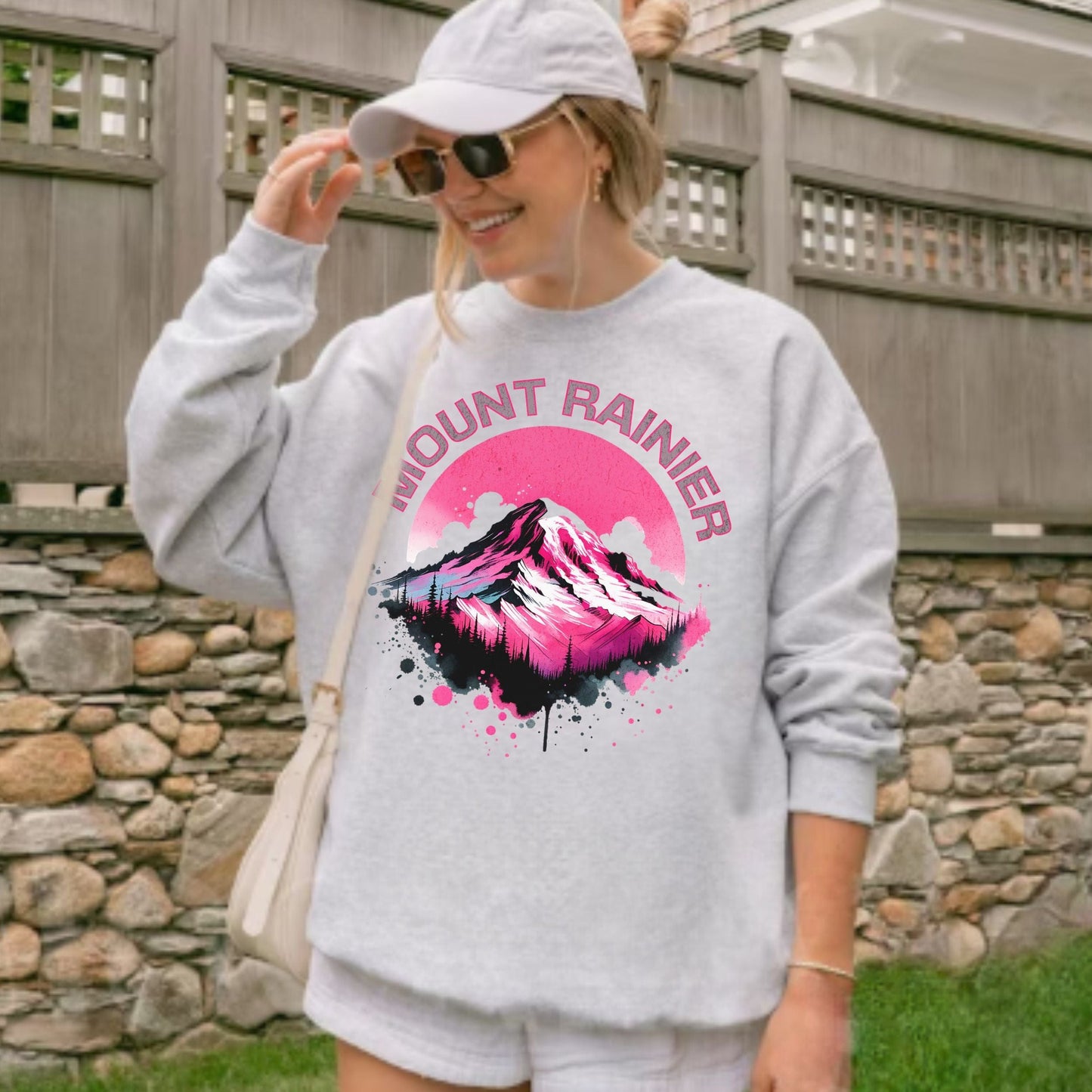 Person wearing a gray sweatshirt with Mount Rainier design outdoors.