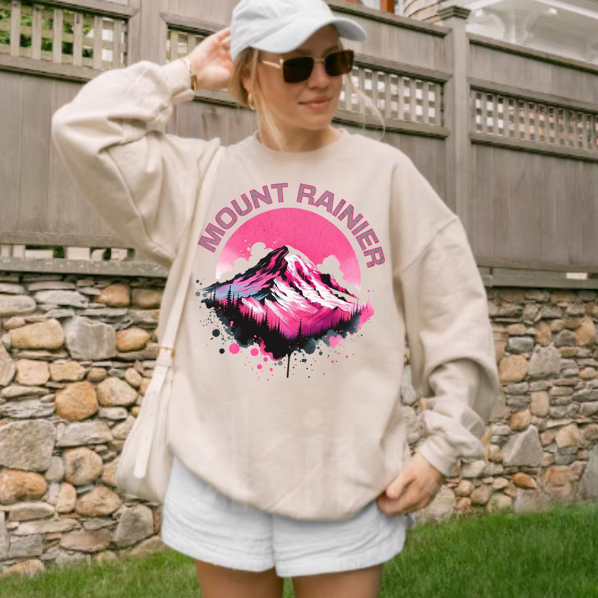 Person wearing a sweatshirt with Mount Rainier design outdoors.