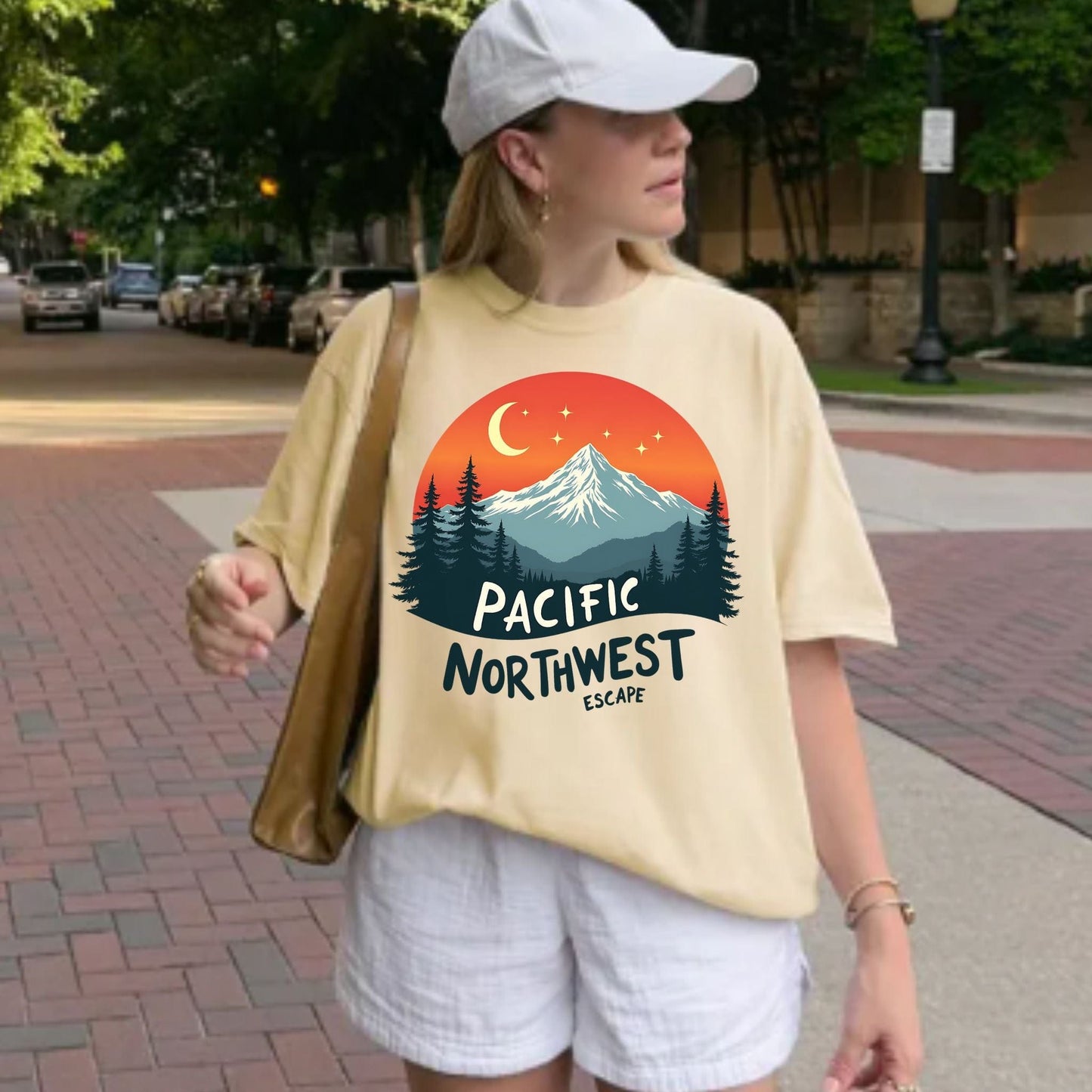 Person wearing a soft, yellow  t-shirt with a Pacific Northwest design on a sidewalk.