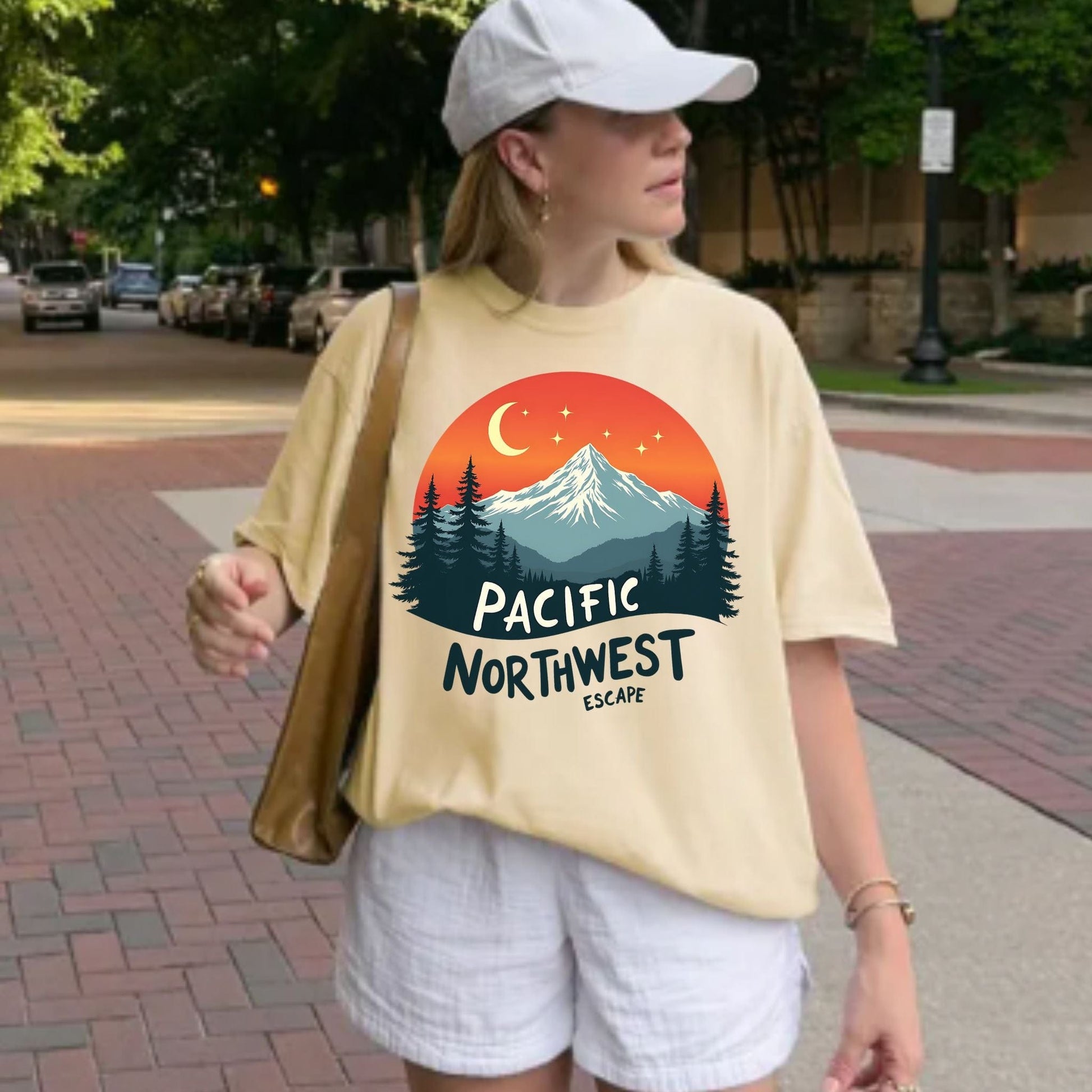 Person wearing a soft, yellow  t-shirt with a Pacific Northwest design on a sidewalk.