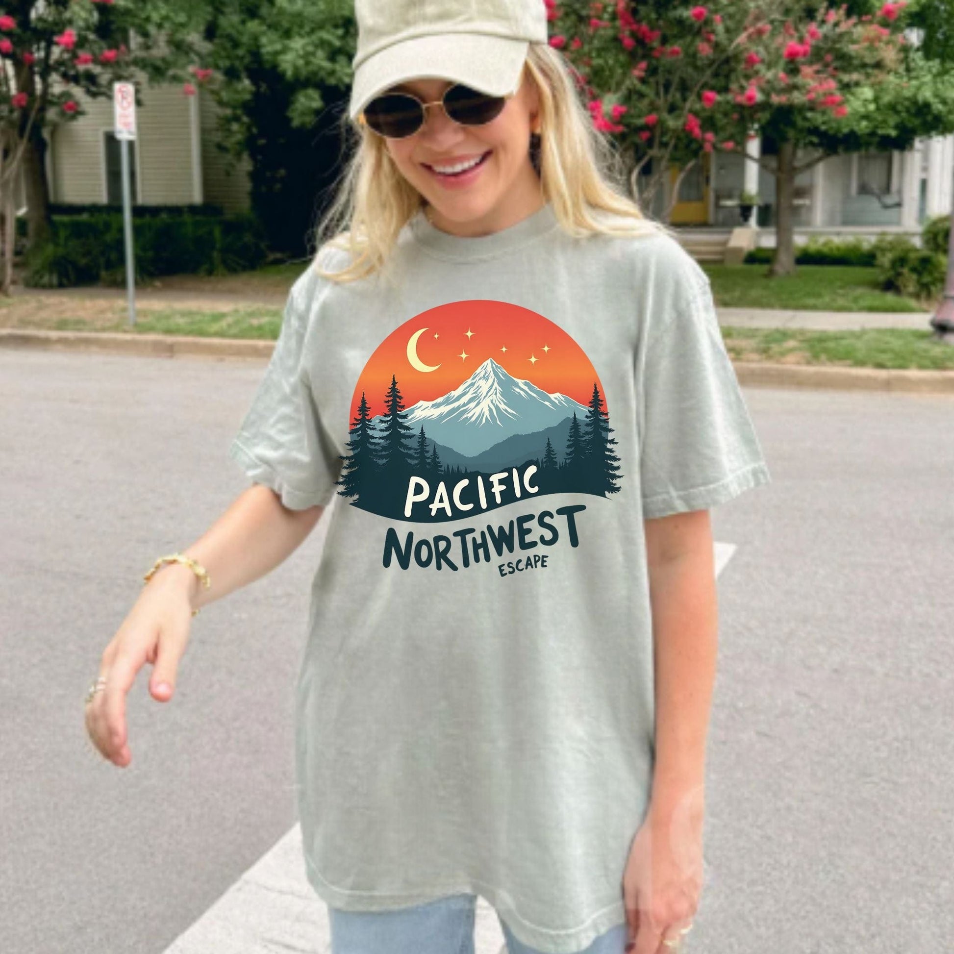 Person wearing a light green t-shirt with a Pacific Northwest design outdoors.