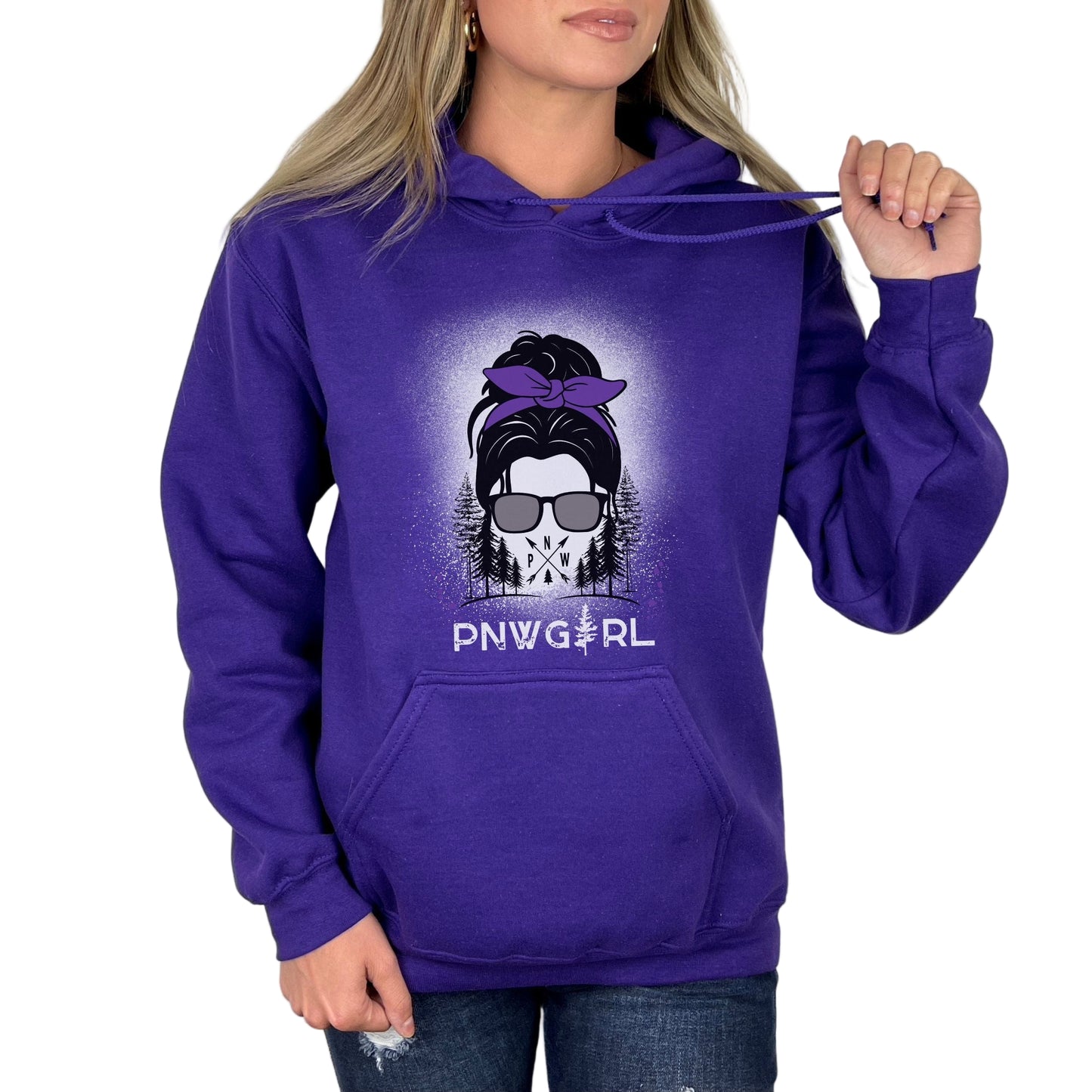 A woman wearing a purple hoodie with an illustration of a girl's face, sunglasses, and the text 'PNWGRL'.