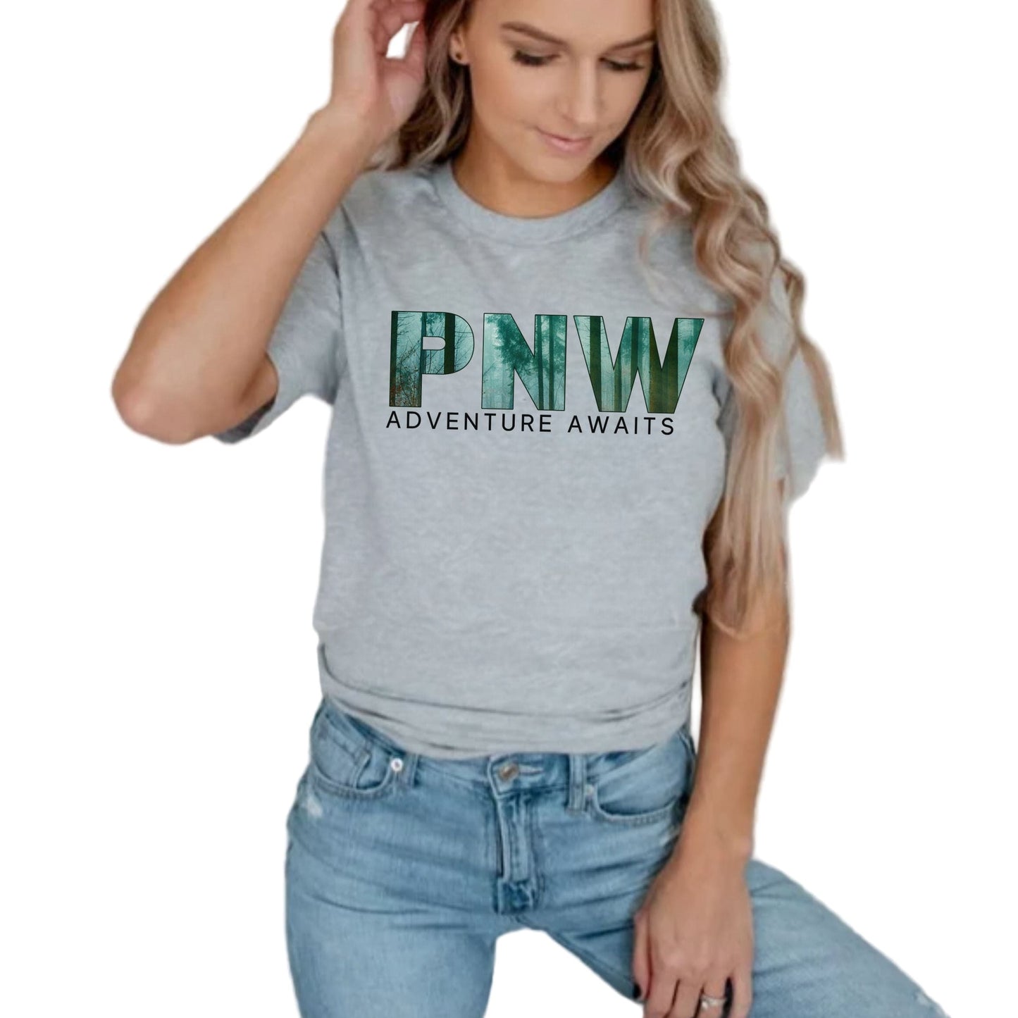 Person wearing a gray t-shirt with 'PNW Adventure Awaits' text and blue jeans against a plain background