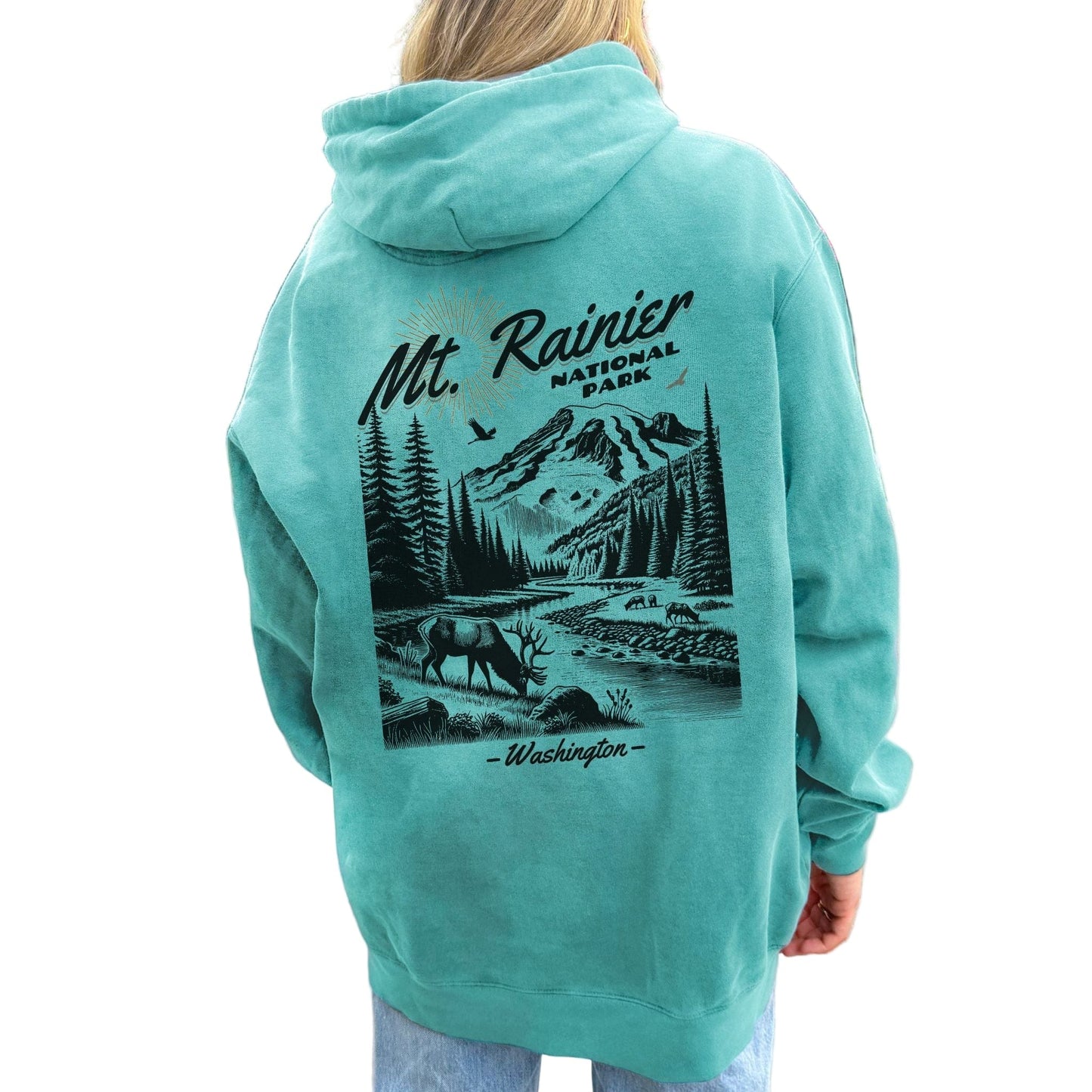 Person wearing a teal hoodie with a graphic of Mount Rainier National Park on the back.