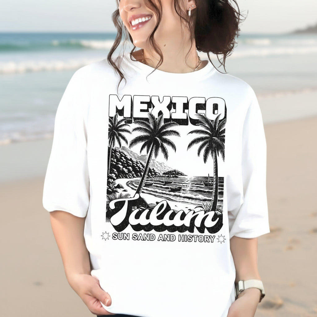 A person wearing a white crew neck t-shirt with a vintage-style graphic print of palm trees and the text 'MEXICO Tulum'.