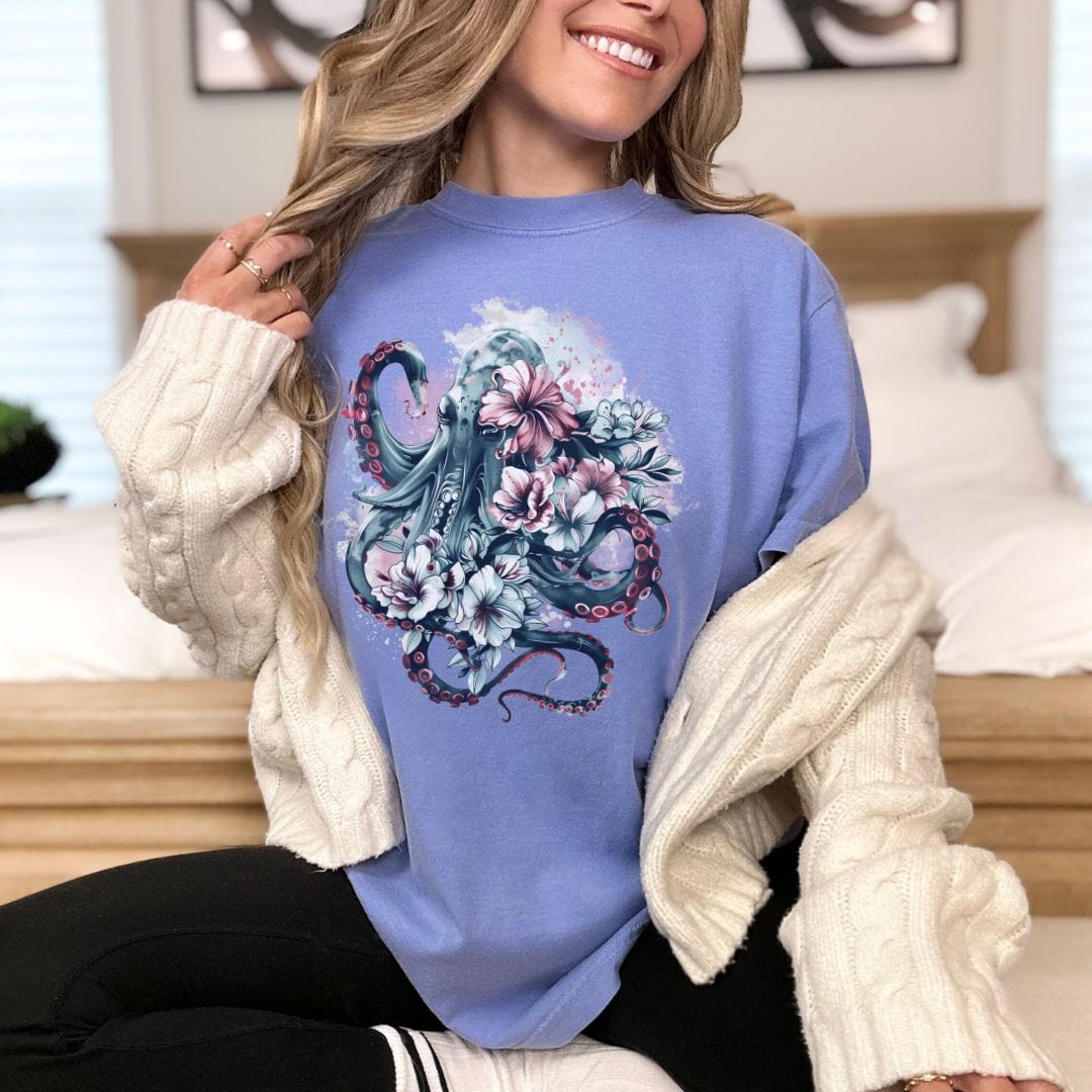 A person wearing a light blue t-shirt with a vintage floral Kraken design.