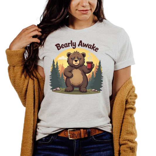 A woman wearing a gray 'Bearly Awake' sleepy bear t-shirt with a graphic of a bear holding a mug.