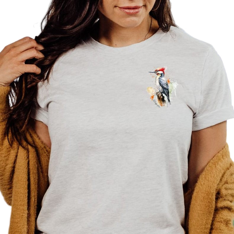 A person wearing a gray t-shirt with a pocket design featuring a woodpecker illustration.