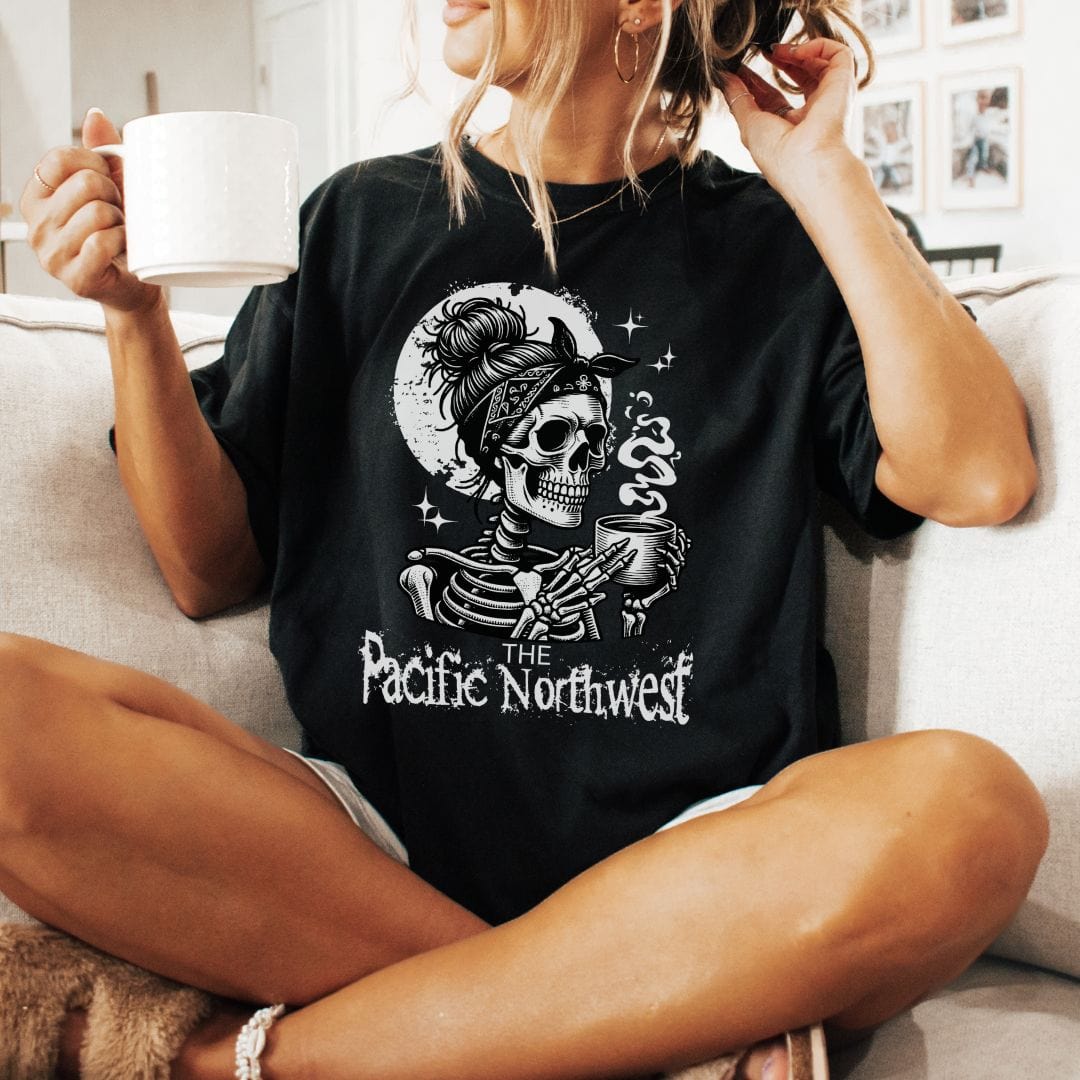 A person wearing a black vintage-style tee with a graphic of a skull holding a mug and the text 'PACIFIC NORTHWEST'.