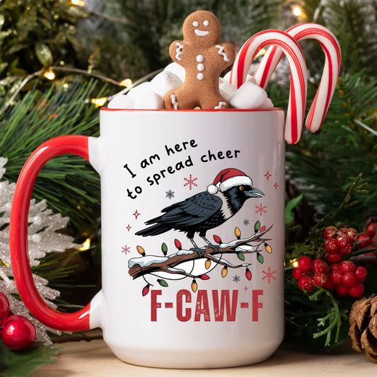 A white ceramic mug with a red handle and red rim, decorated with a black raven wearing a Santa hat, holiday lights, snowflakes, and the text 'I am here to spread cheer' and 'F-CAW-F'. The mug is filled with whipped cream, marshmallows, a gingerbread cookie, and candy canes, set against a festive Christmas background with pine branches, lights, and berries.