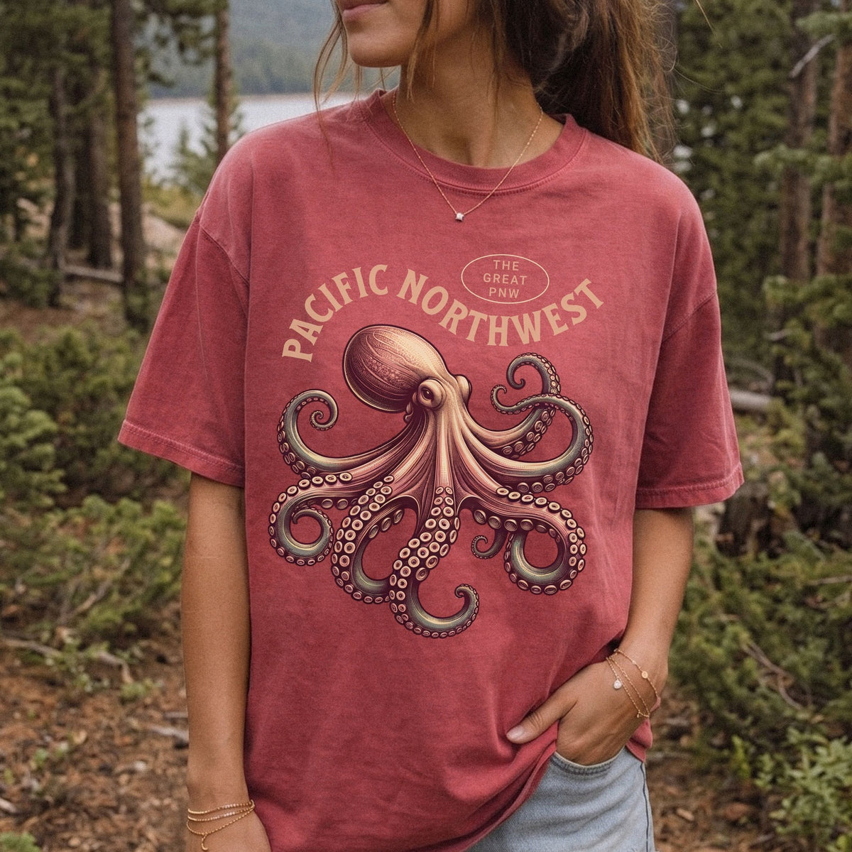 A woman wearing a washed crimson graphic t-shirt with a large octopus design and the text 'PACIFIC NORTHWEST' and 'THE GREAT PNW'.