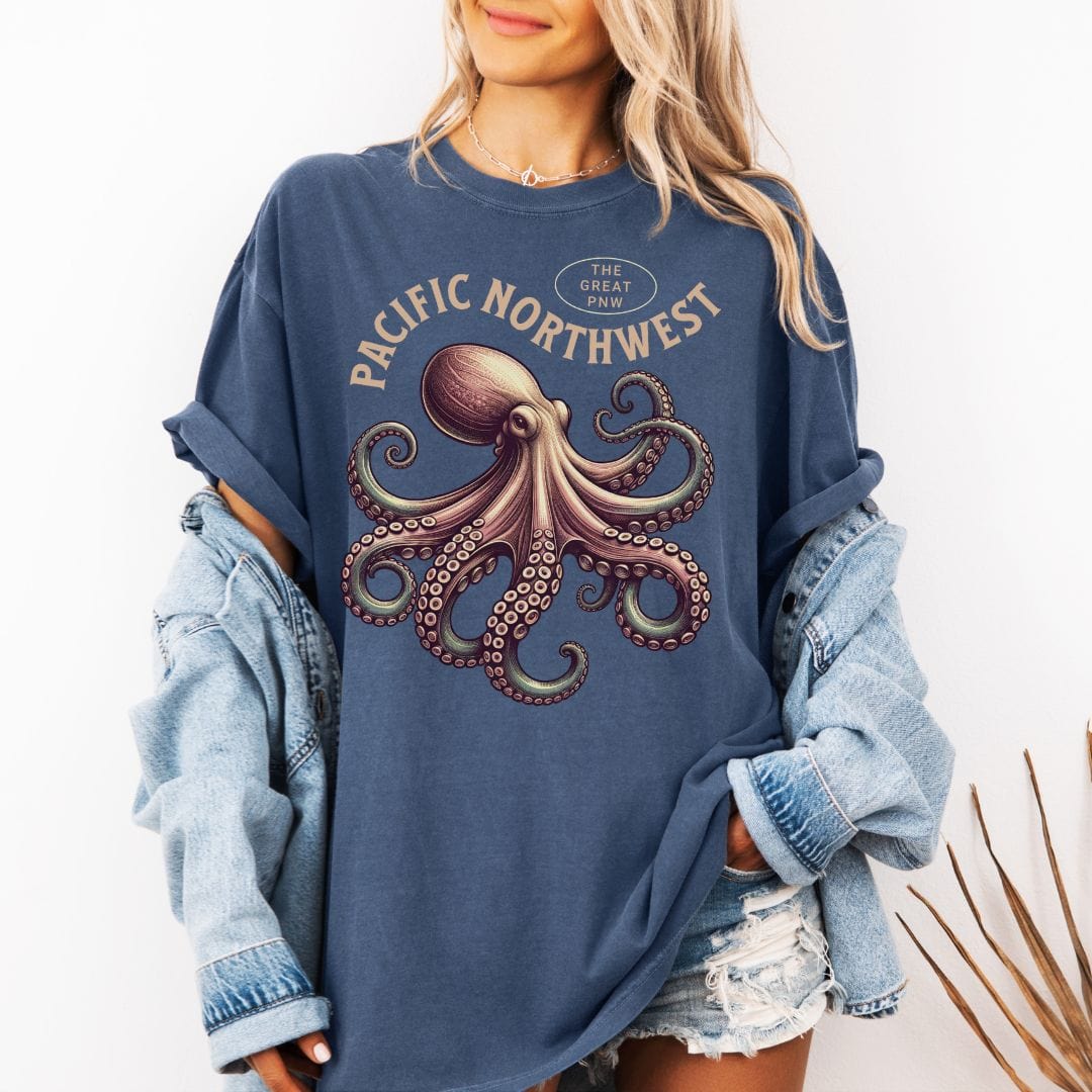Person wearing a blue t-shirt with an octopus graphic and 'Pacific Northwest' text, paired with a plaid shirt.