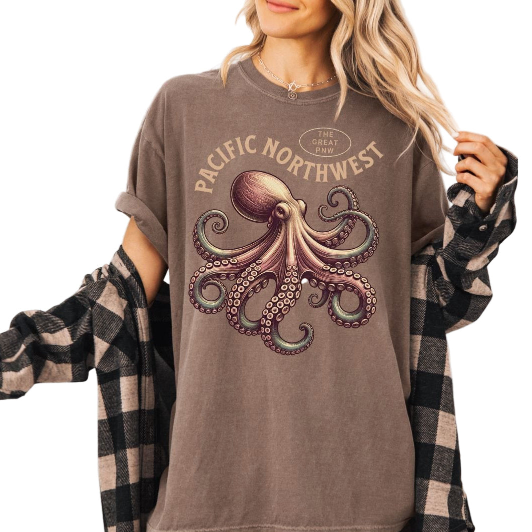 Person wearing a brown t-shirt with an octopus graphic and 'Pacific Northwest' text, paired with a plaid shirt.