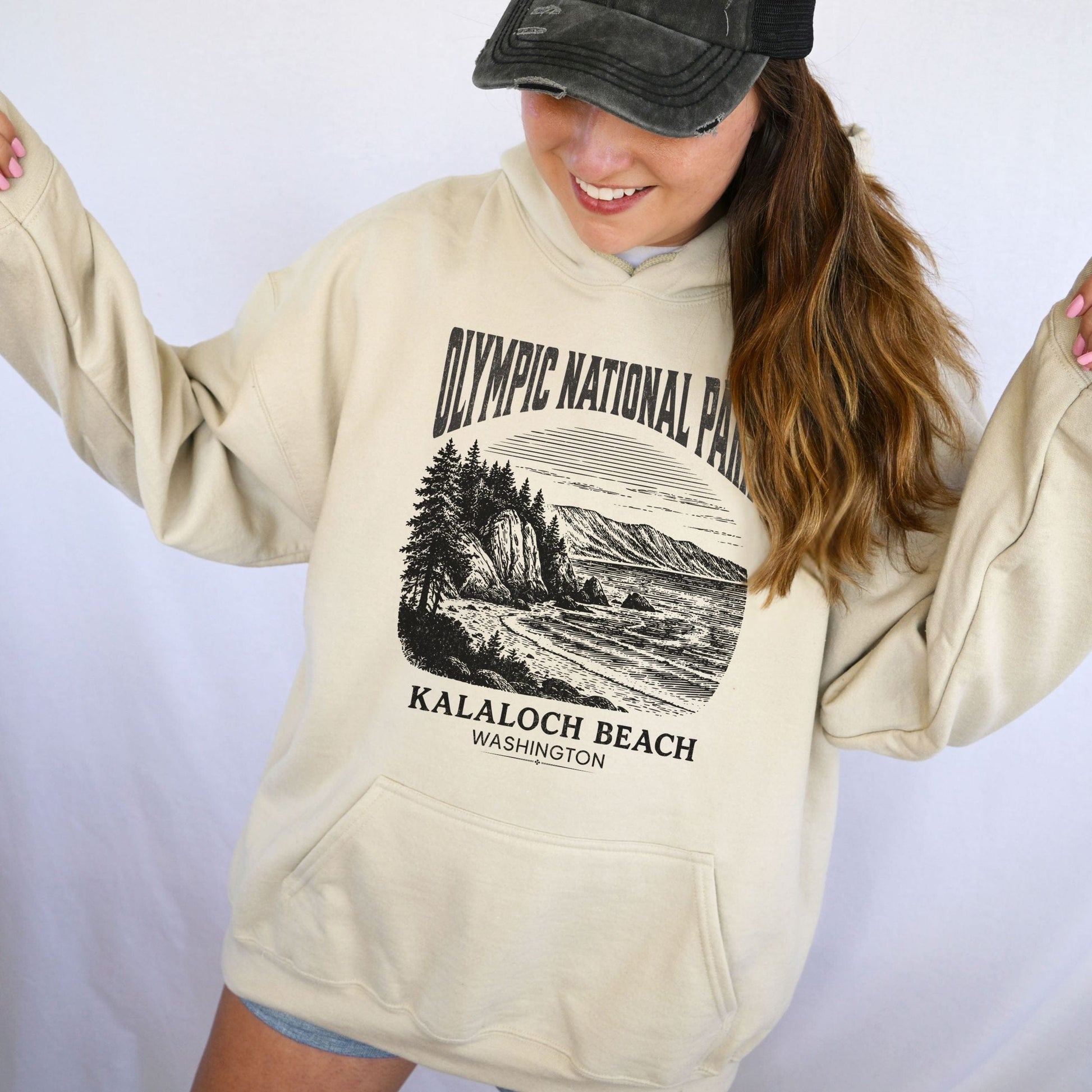 Person wearing a beige hoodie with Olympic National Park design on a plain background
