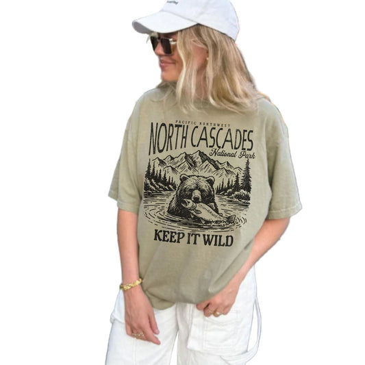 Person wearing a t-shirt with 'North Cascades National Park' design outdoors.