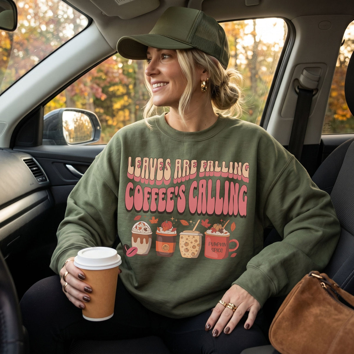 Woman wearing a military green fall coffee crewneck with pumpkin spice drinks, autumn leaves, and retro seasonal graphic