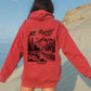 Person wearing a red hoodie with 'Mt. Rainier National Park, Washington' design on the back, standing on a beach.
