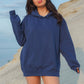 Person wearing a blue hoodie on a sandy hillside with a clear sky.
