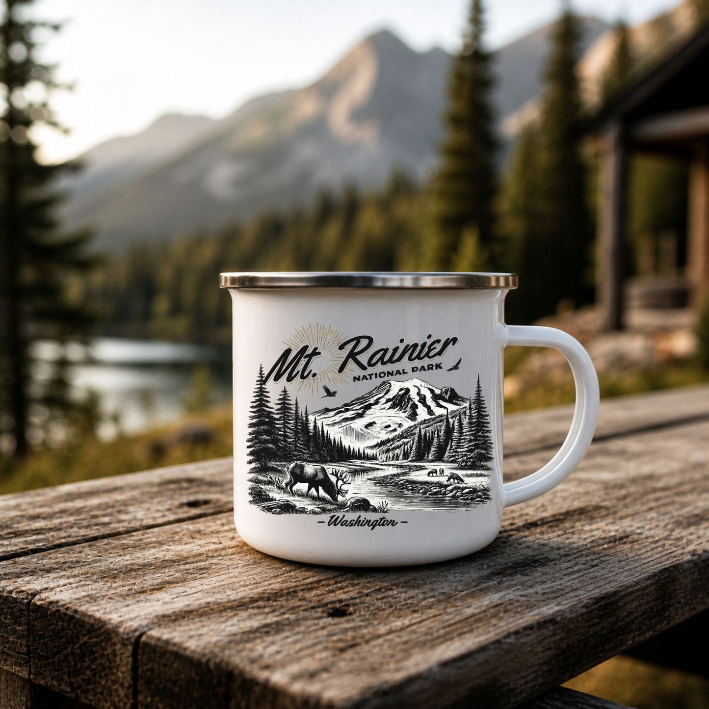White Mt. Rainier National Park enamel camp mug on a rustic wooden table with a lake, forest, mountains, and cabin in the background.