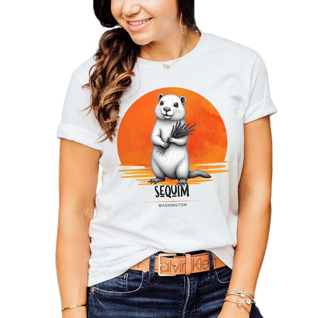 A woman wearing a white t-shirt with a nature-inspired design featuring a marmot and a sunset in the background.